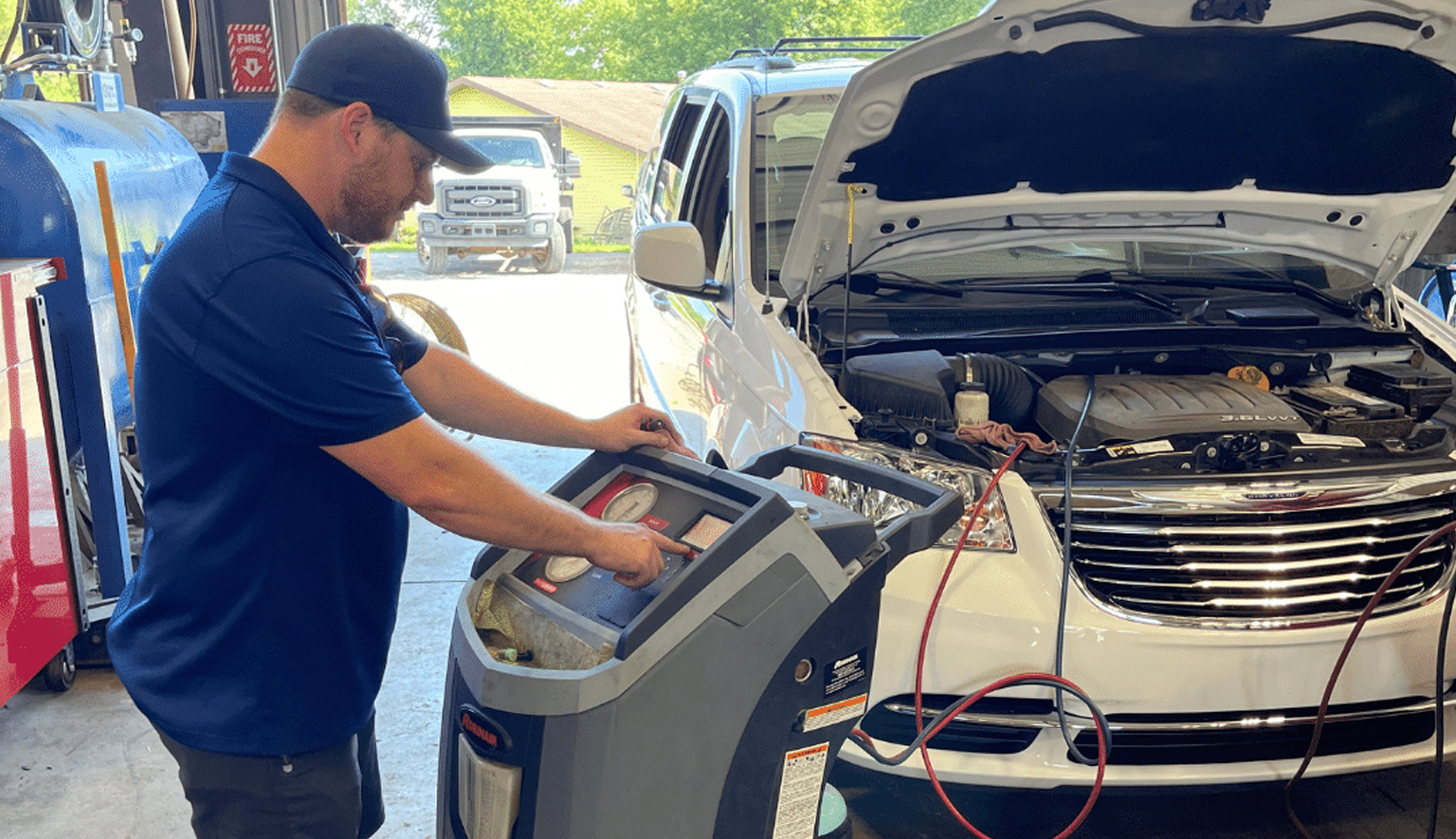 Technician performing automotive air conditioning diagnostics and refrigerant service