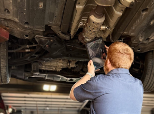Technician inspecting exhaust components for leaks, cracks, and loose hangers